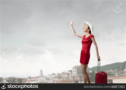 Woman in red. Young woman in red dress with red luggage gesturing with hand