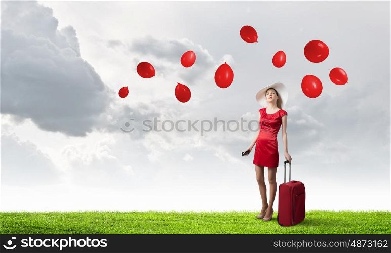 Woman in red. Young woman in red dress with red luggage with mobile phone in hand