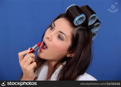 Woman in rollers applying lipstick