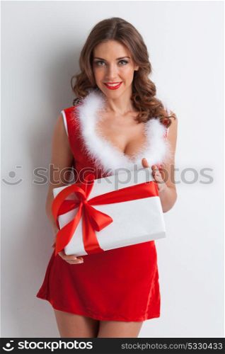 Woman in santa costume with gift. Sexy young woman in santa claus costume holding christmas gift box