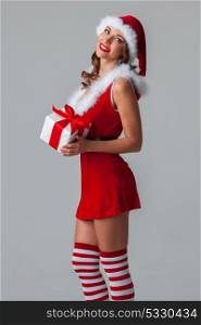 Woman in santa costume with gift. Sexy young woman in santa claus costume holding christmas gift box