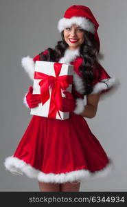 Woman in santa dress with gift. Beautiful young woman in Santa dress celebrating Christmas holding gift box