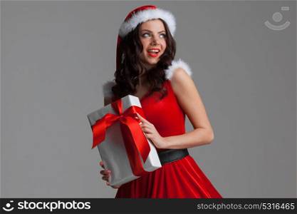Woman in santa hat with gift. Beautiful young woman in Santa hat celebrating Christmas holding gift box