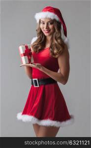 Woman in santa hat with gift. Beautiful young woman in Santa hat celebrating Christmas holding gift box