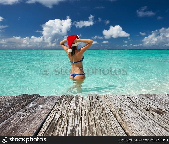 Woman in santa&rsquo;s hat in bikini at tropical beach