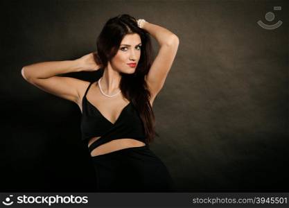 woman in sensual black dress on dark. Party celebration concept. Magnificent long hair woman red lipstick wearing black evening dress pearls necklace on dark