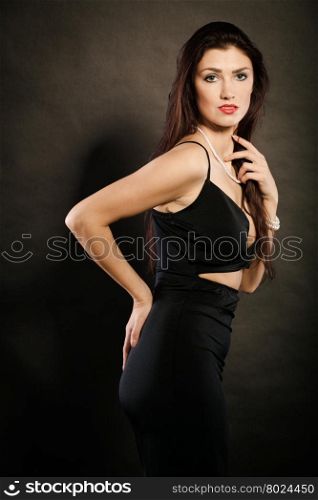woman in sensual black dress on dark. Party celebration concept. Magnificent long hair woman red lipstick wearing black evening dress on dark