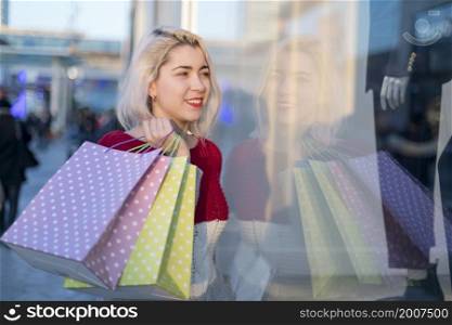 Woman in shopping. Happy woman with shopping bags enjoying in shopping. Consumerism, shopping, lifestyle concept. beautiful young blonde woman smiling with shopping bags outside