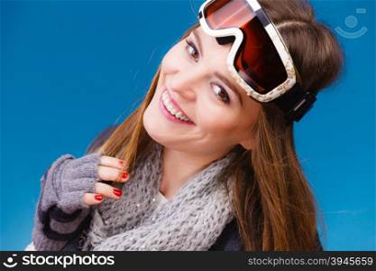 Woman in ski googles warm winter clothing portrait. Woman skier girl wearing warm clothing ski googles portrait. Winter sport activity. Beautiful sportswoman on blue studio shot