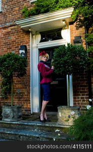 Woman in skirt and jacket on front door step
