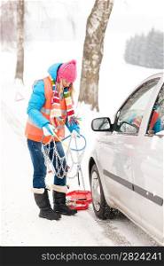 Woman in snow car problems tire chains breakdown smiling winter