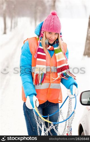 Woman in snow car problems tire chains breakdown smiling winter