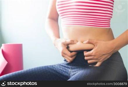 Woman in sport clothing holding excessive belly fat, Healthy and Beauty concept