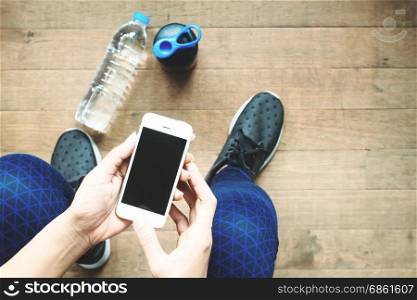 Woman in sport pants and shoes using smartphone, Top view