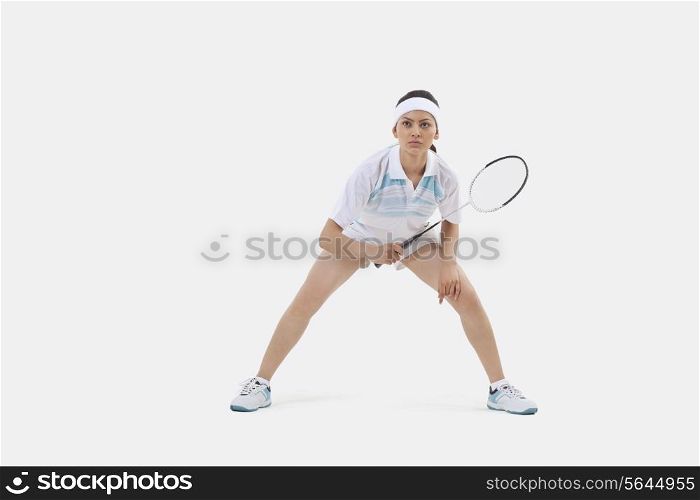 Woman in sports wear playing badminton against white background