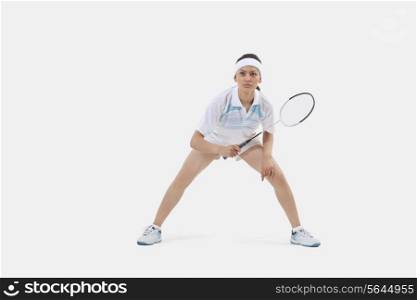 Woman in sports wear playing badminton against white background
