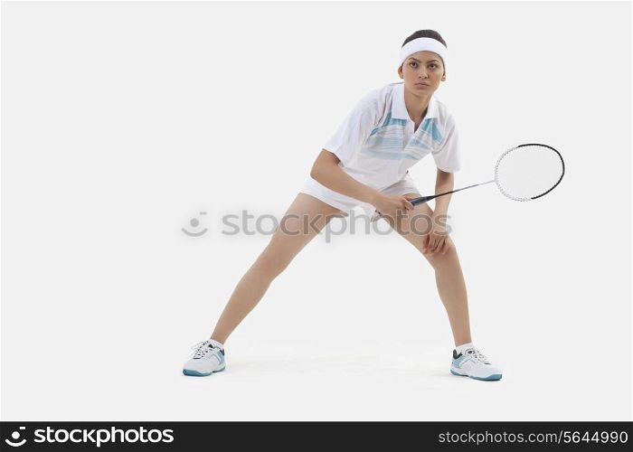Woman in sports wear playing badminton isolated over white background
