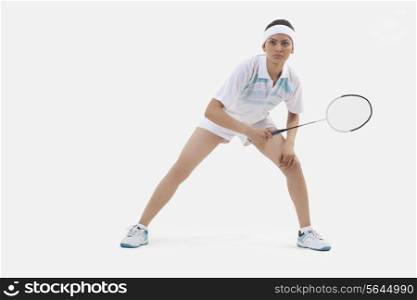Woman in sports wear playing badminton isolated over white background