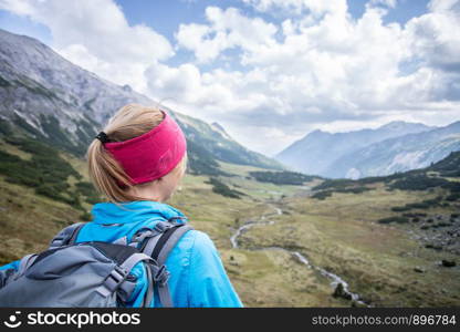 Woman in sportswear and with backpack enjoys the view in the mountains
