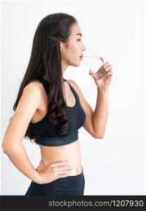 Woman in sportswear drinking water in a fitness gym. Healthy lifestyle and hydration concept.. Woman in sportswear drinking water in fitness gym.