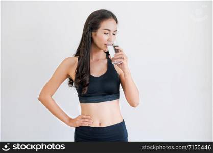 Woman in sportswear drinking water in a fitness gym. Healthy lifestyle and hydration concept.