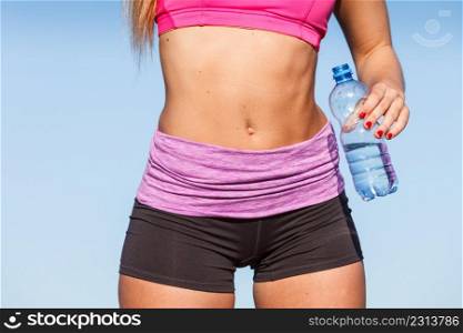 Woman in sportswear takes a break to rehydrate drinking water from plastic bottle, resting after sport workout outdoor. Woman drinking water after sport gym outdoor