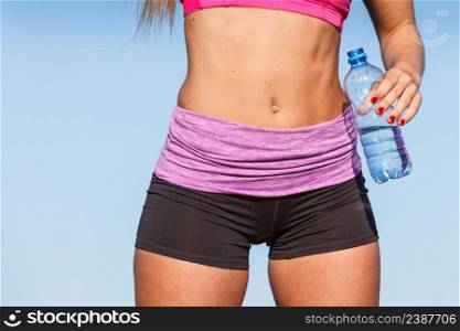 Woman in sportswear takes a break to rehydrate drinking water from plastic bottle, resting after sport workout outdoor. Woman drinking water after sport gym outdoor