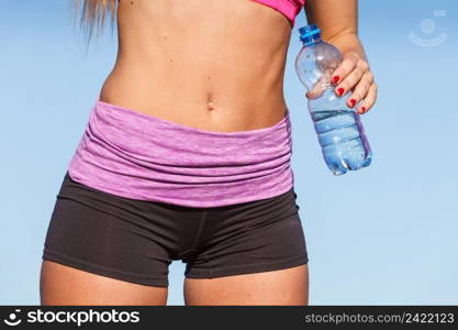 Woman in sportswear takes a break to rehydrate drinking water from plastic bottle, resting after sport workout outdoor. Woman drinking water after sport gym outdoor