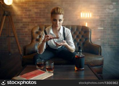Woman in strict clothes smoking cigar at the table, retro fashion, gangster style. Vintage business lady. Woman in strict clothes smoking cigar, gangster