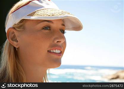 Woman in sun visor at beach head and shoulders close up