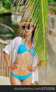 Woman in sunglasses near palm tree wearing hat