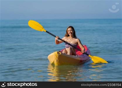 woman in swimsuit paddling a kayak boat in the sea