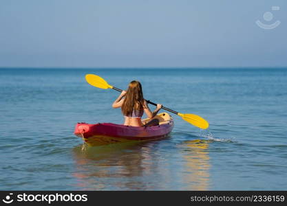 woman in swimsuit paddling a kayak boat in the sea