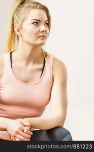 Woman in tank top sitting on sofa indoor getting ready for exercises having serious face expression being confident.. Woman in sportswear being serious