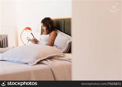 Woman in the bed writting notes on her diary