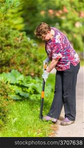 Woman in the garden pulling weeds out with the gardening equipment