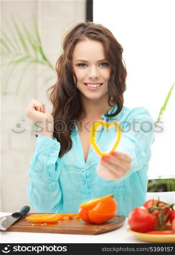 woman in the kitchen cutting vegetables and holding heart shape