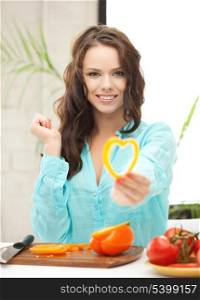 woman in the kitchen cutting vegetables and holding heart shape