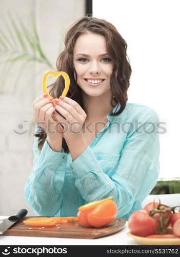 woman in the kitchen cutting vegetables and holding heart shape