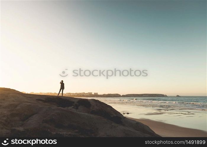 Woman in the top of a rock enjoying the beach view