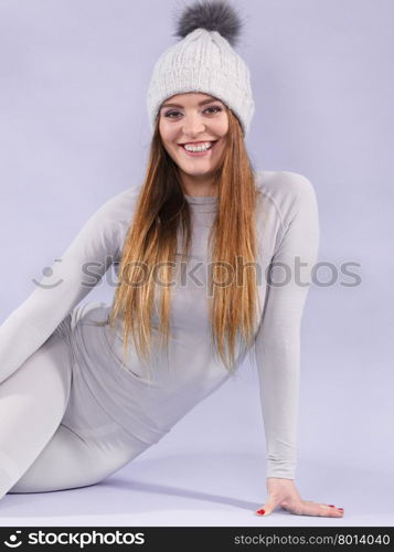 woman in thermal underwear. Attractive woman in winter cap and gray sports thermolinen underwear for skiing training studio shot on violet. Long sleeves top and leggings