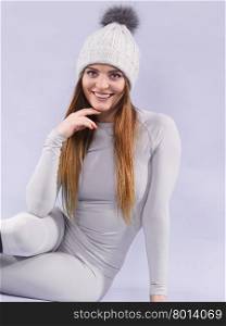 woman in thermal underwear. Attractive woman in winter cap and gray sports thermolinen underwear for skiing training studio shot on violet. Long sleeves top and leggings