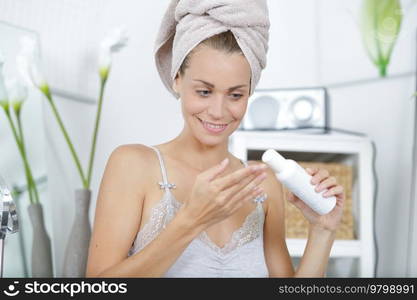 woman in towel on head putting cream on