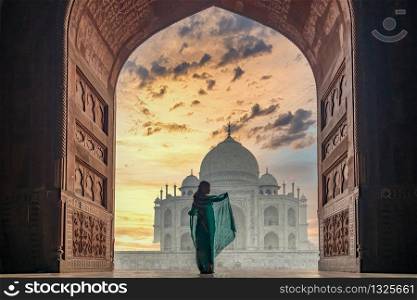 Woman in traditonal culture dress saree or sari in the Taj Mahal, Taj Mahal is most beautiful white marble mausoleum in the Indian city, Agra, Uttar Pradesh, India.