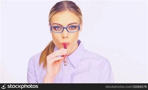 Woman in trendy stylish glasses smoking an e-cigarette puffing out a cloud of smoke at the camera isolated on white