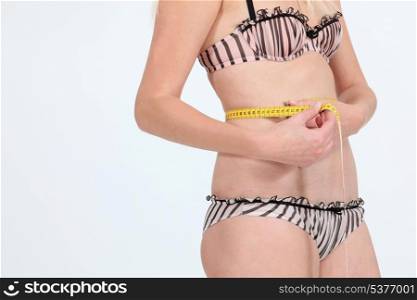 Woman in underwear measuring waist