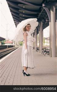 Woman in vintage dress with old suitcase on the railroad station. Woman in vintage dress