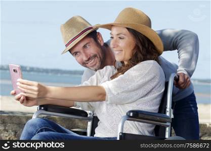 woman in wheelchair and her husband taking selfie outdoors