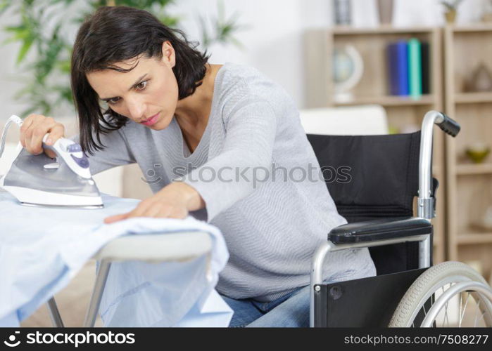 woman in wheelchair during ironing at home