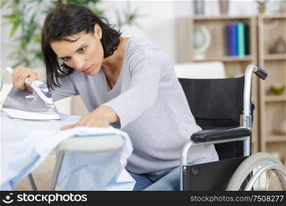 woman in wheelchair during ironing at home